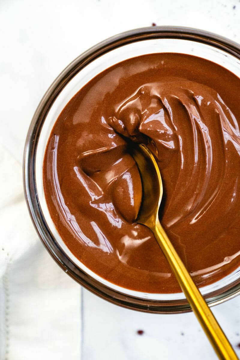 A bowl of creamy chocolate pudding with a golden spoon dipped in it