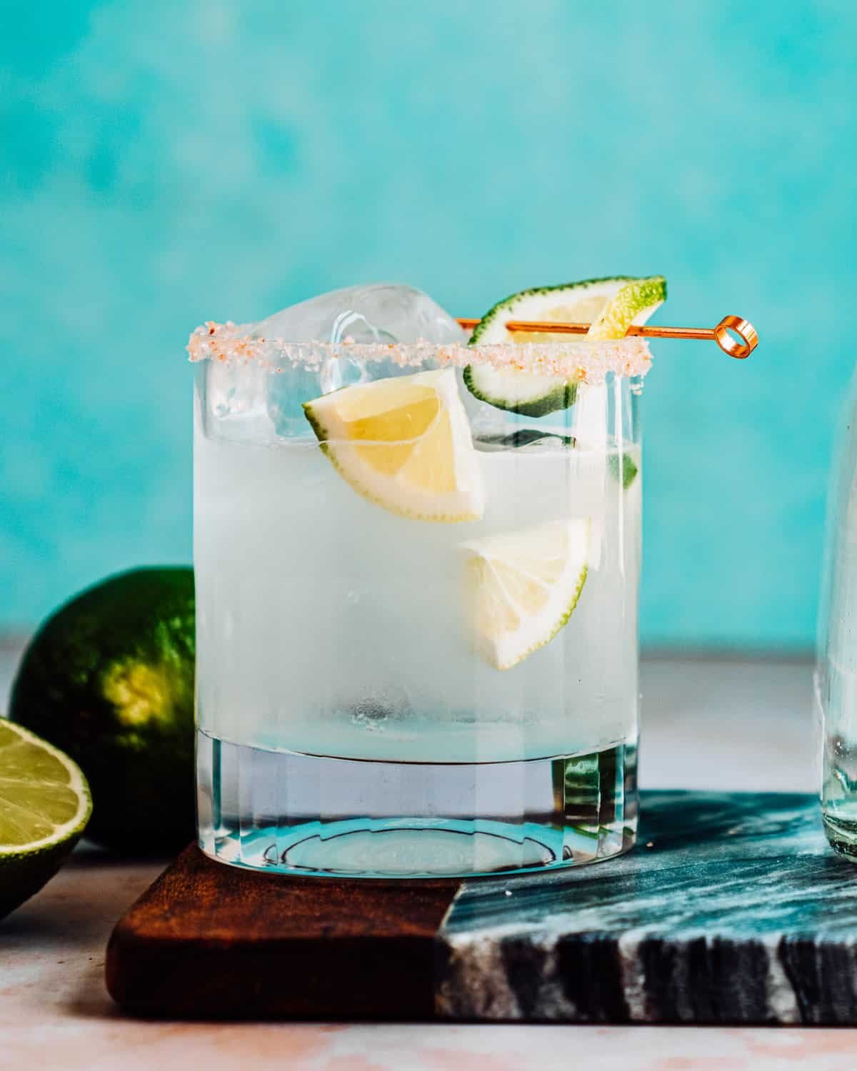 Margarita recipe in glass with limes and salt rim