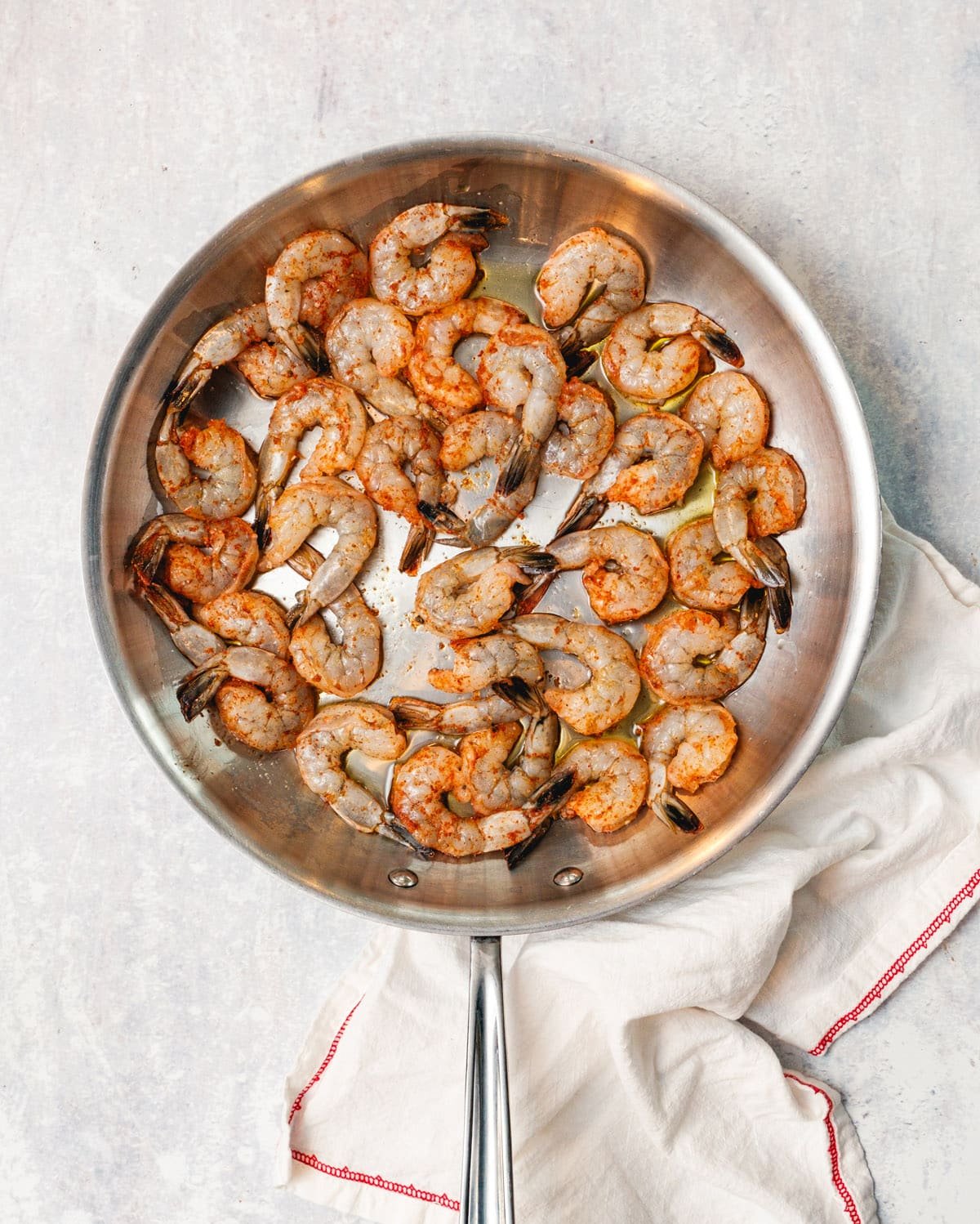 Overhead view of shrimp mid way cooked in a metal frying pan